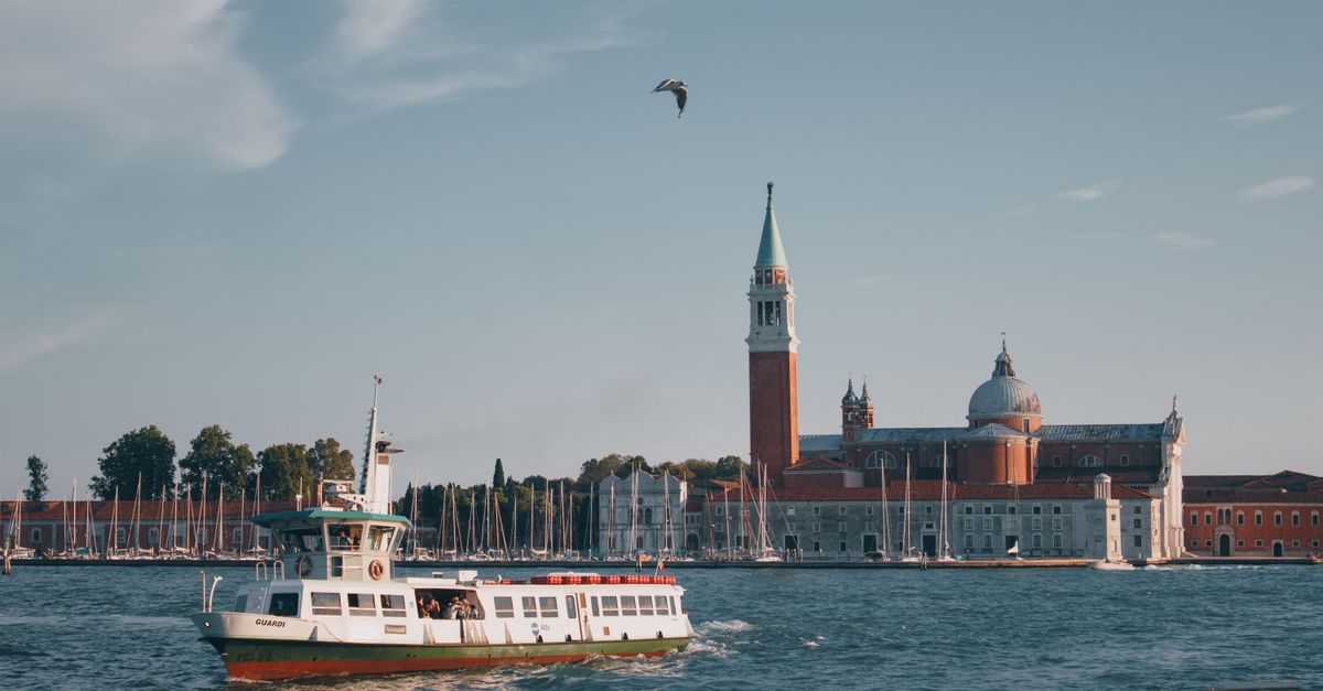 Scenic view of San Giorgio Maggiore with boats on the Grand Canal in Venice, Italy, under a clear summer sky.